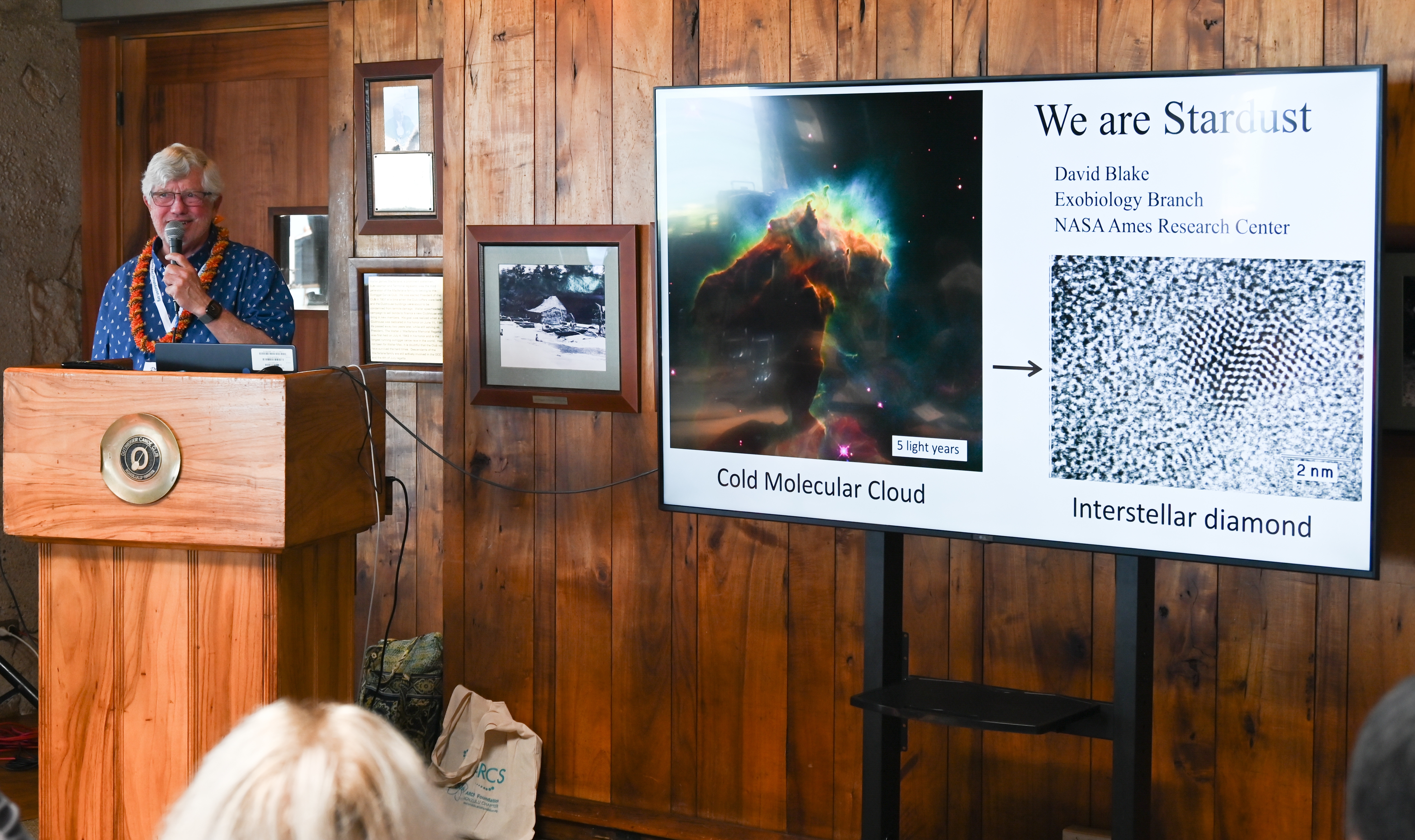 Dr. David Blake talking on "We Are Stardust" David Blake by big TV screen
